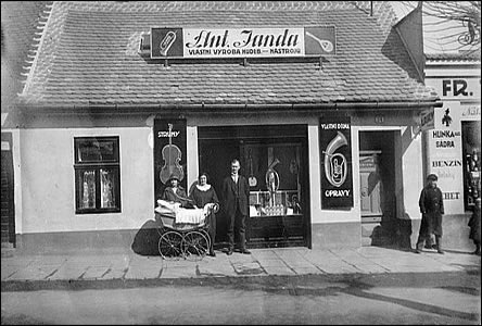 Pan Janda ped svou firmou vedle obchodu pana Touska.