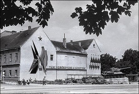 Pomník s tankem za radnicí i s částí domu vedle vojenské správy.
