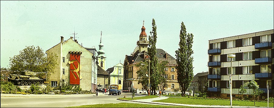 Panoramatický snímek Zámeckého námstí s pohledem od pomníku s tankem k radnici a kostelu.