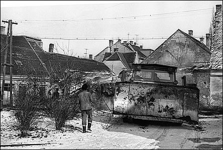 Buldozer se připravuje k demolici domků židovského městečka.