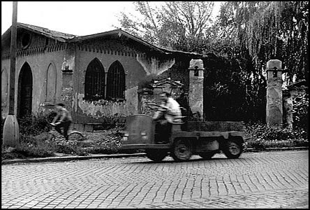 Bateriový vozík uhání do msta okolo brány a kaple idovského hbitova.